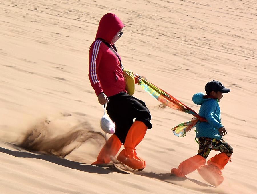 Tourists enjoy themselves at Mingsha Hill desert