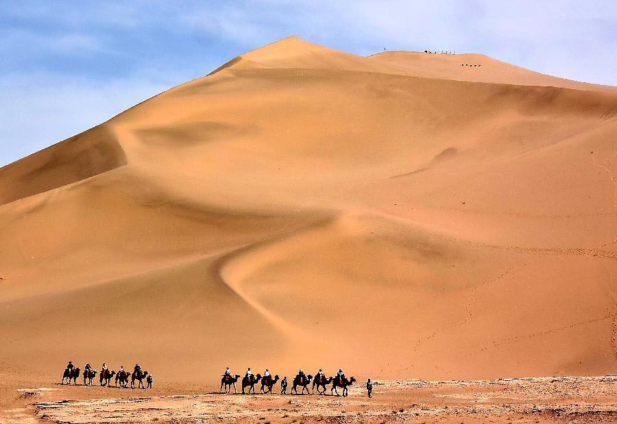 Tourists enjoy themselves at Mingsha Hill desert