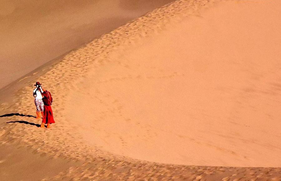 Tourists enjoy themselves at Mingsha Hill desert