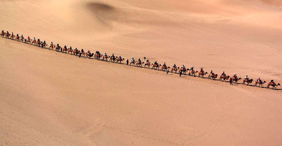 Tourists try camel riding at Mingsha Hill desert