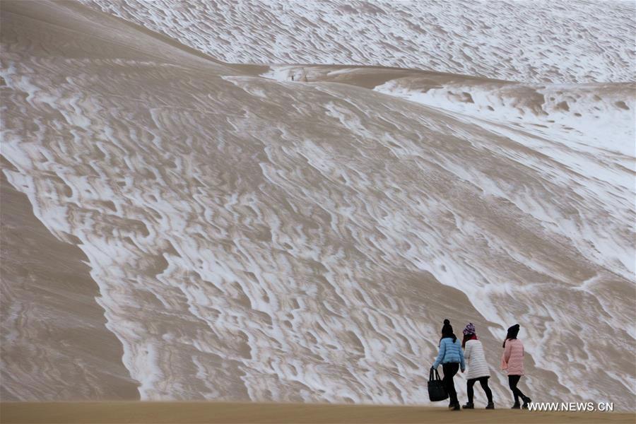 Tourists enjoy snow scenery in Dunhuang's desert