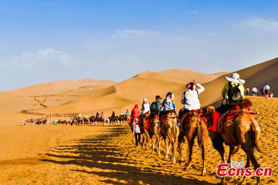 Tourists visit Mingsha Mountain in Dunhuang