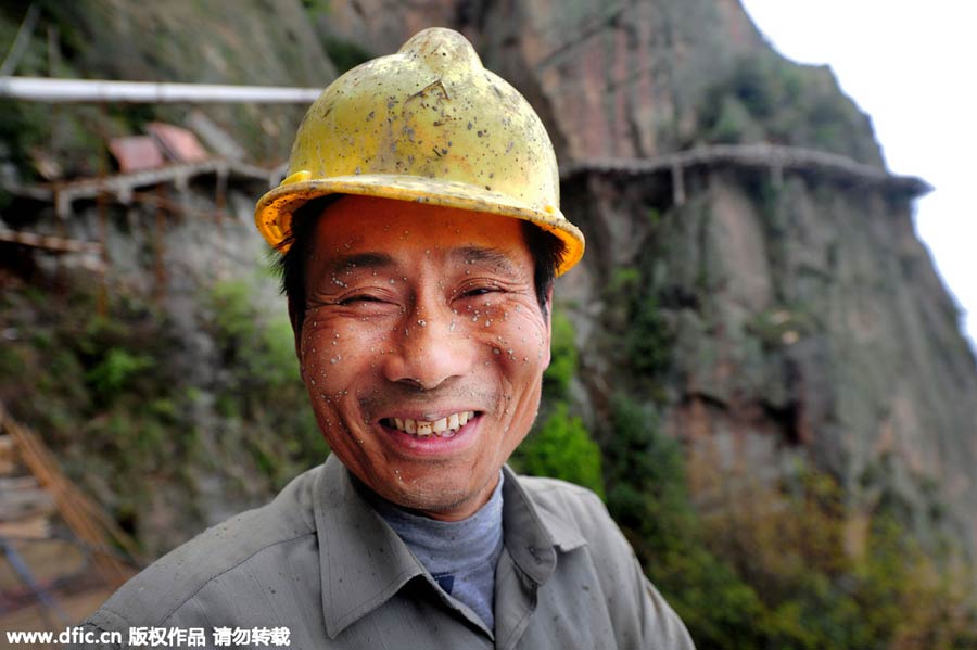 Workers balance on planks to build mountain road