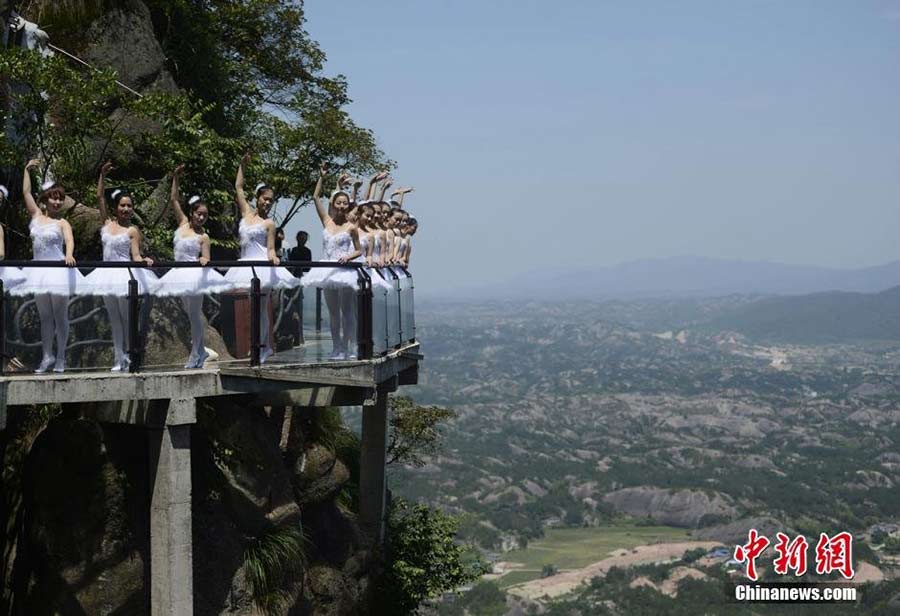 Dancers perform ballet on cliff, glass walkway