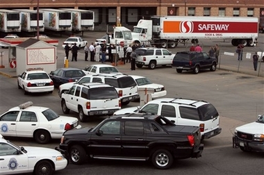 Police vehicles officers block the entrance to a Safeway Inc. distribution center in Denver while officers respond to a gunman who opened fire and killed one person while wounding five others Sunday, June 25, 2006. Police report that the gunman was found dead in the facility. [AP]