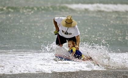 A man and his young daughter play in the surf at Doheny State Beach in Dana Point, Calif., Wednesday, May 26, 2004. As many as 1.5 million people are sickened by bacterial pollution on Southern California beaches each year, study finds. [AP Photo]