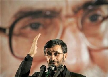 Iranian President Mahmoud Ahmadinejad gestures while standing under a huge picture of Iran's Supreme Leader Ayatollah Ali Khamenei in Tehran, June 3, 2006. Iran's reply to a big power offer of incentives to end sensitive nuclear work asks for a timeline to implement the package and specifics on security arrangements, two Iranian experts said in a Web site report on Thursday.