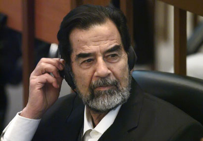 Ousted Iraqi leader Saddam Hussein adjusts his headphones as he listens to witness testimony during his trial held in Baghdad's heavily fortified Green Zone October 17, 2006. 