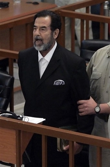 Former Iraqi leader Saddam Hussein yells at the court as he receives his verdict as a bailiff attempts to restrain him during his trial held under tight security in the heavily fortified Green Zone, in Baghdad, Iraq, Sunday, Nov. 5, 2006. Saddam and two others were convicted and sentenced to death by hanging for war crimes in the 1982 killings of 148 people in the town of Dujail. (AP