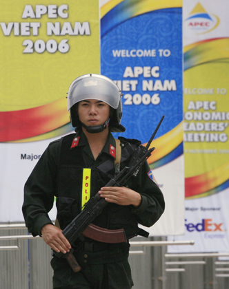 A police official keeps guard close to banners fastened from the gates of the National Convention Center, the site of the upcoming Asia-Pacific Economic Cooperation (APEC) meeting, in Hanoi November 12, 2006. 