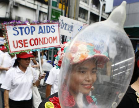 A woman waves a condom while taking part in a parade to commemorate World AIDS Day in Bangkok December 1, 2006. 