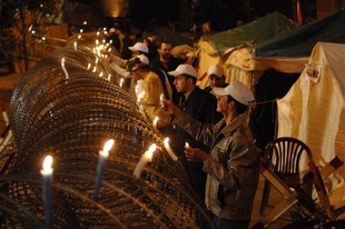Lebanese supporters of Hezbollah and their allies light candles on a barbed wire near the Government House, after the funeral of Ahmed Ali Mahmoud who was killed Sunday during clashes which erupted between groups of Shiites and Sunnis, in downtown Beirut, Lebanon, Tuesday Dec. 5, 2006. Shiites on Tuesday buried a young man killed in street clashes in a Sunni Muslim neighborhood as the country's army commander warns the military may not be able to contain any further protests linked to Lebanon's tense political standoff. (AP 