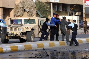 Iraqi police drag away a man protesting against U.S. soldiers, blaming them for the situation in Iraq, at the site following a car bomb explosion Baghdad, Iraq, Thursday, Dec. 7, 2006. (AP