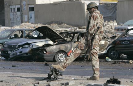 An Iraqi soldier inspects the scene of a car bomb attack at a parking lot of Mahmoun University in Baghdad December 11, 2006. The attack killed one person and wounded four others, including two policemen. 