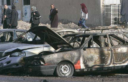 Burnt vehicles lie at the scene of a car bomb attack in a parking lot of Mahmoun University in Baghdad December 11, 2006.