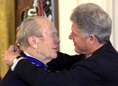 U.S. President Bill Clinton helps former President Gerald Ford affix the Medal of Freedom around his neck at the White House in Washington in this August 11, 1999 file photo. Ford, who took office from an embattled Richard M. Nixon, has died, according to a statement from his widow on December 26, 2006. 