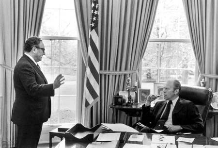 Former U.S. Secretary of State Henry Kissinger (L) gives former President Gerald Ford the latest information on the situation in South Vietnam, during a meeting at the White House in this April 29, 1975 file photo. Ford, who took office from an embattled Richard M. Nixon, has died, according to a statement from his wife Bette on December 26, 2006. 