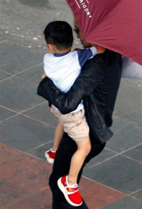 Under a big umbrella held by her bodyguard, only his arm is seen on right, American actress Angelina Jolie holds her newly adopted son Pax Thien Jolie as she rushes to a VIP room at the Tan Son Nhat airport in Ho Chi Minh city, southern Vietnam, Monday, March 19, 2007. Jolie and her children headed to Vietnamese capital Hanoi. (AP Photo