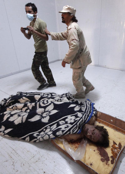 Gadhafi's corpse in display, rumors on autopsy, handover