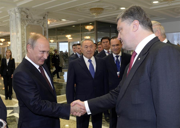 Putin shakes hands with Poroshenko